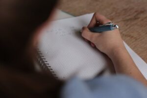 person writing down math notes in notebook