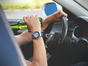 man drinking beer and driving